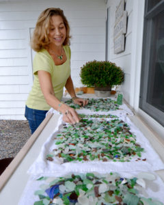 Swampscott. Sonja Grondstra outside her studio. She has rinsed sea glass she collected from local beaches and is letting it dry on towels outside.